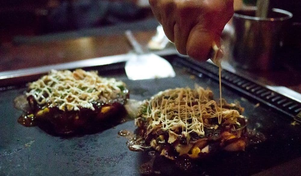 Der Koch gibt dem Okonomiyaki den letzten Schliff mit ein wenig Mayonnaise! - Flickr: Hajime Nagahata